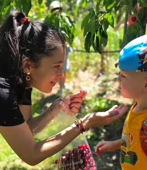 Adult interacționând cu blândețe cu un copil în curtea Hera Kids.