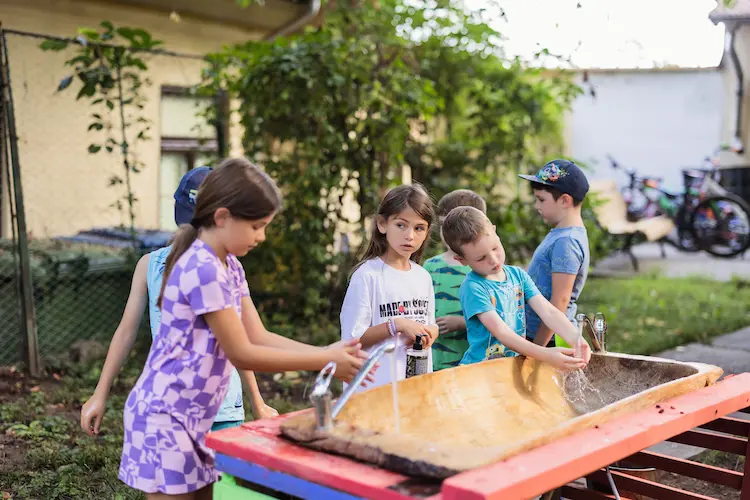 Copii la Hera Kids din Târgoviște, jucându-se cu apă în curte.