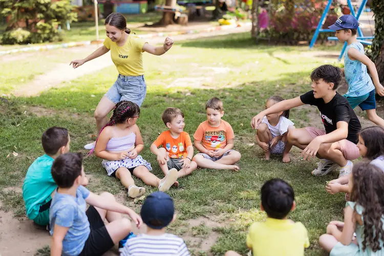 Copii și coordonatori la jocuri de grup în curtea Hera Kids.