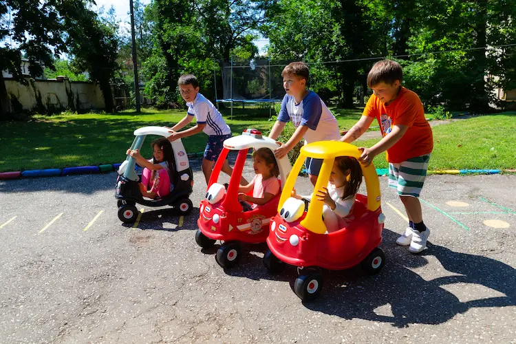 Copii jucându-se cu mașinuțe în curtea Hera Kids, la Școala de Vară.