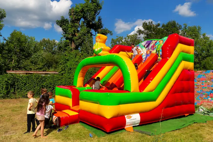 Copii pe toboganul gonflabil din curtea Hera Kids, la Școala de Vară.